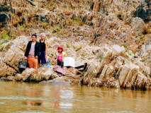 Moradores locais junto às rochas na margem do rio Mekong aguardando para embarcar no slow boat entre Pakbeng e Huay Xai