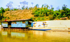 Casa tradicional sobre estacas na margem do rio Mekong entre Pakbeng e Huay Xai vista durante uma viagem de slow boat no norte do Laos